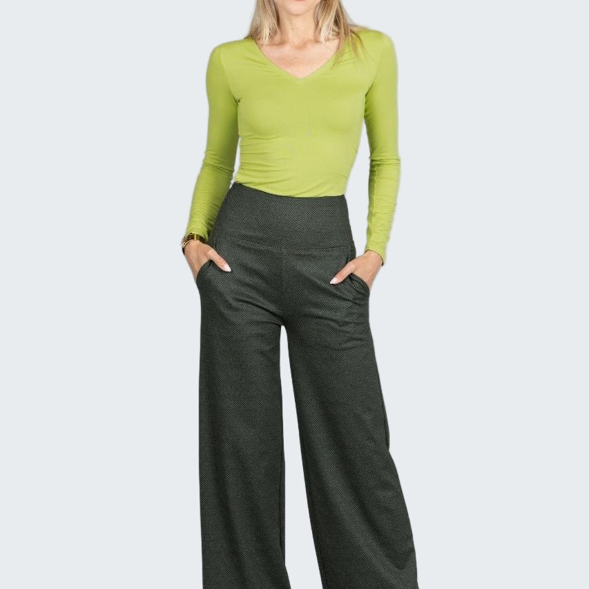 Woman wearing a green top and dark green wide-leg pants on a white background