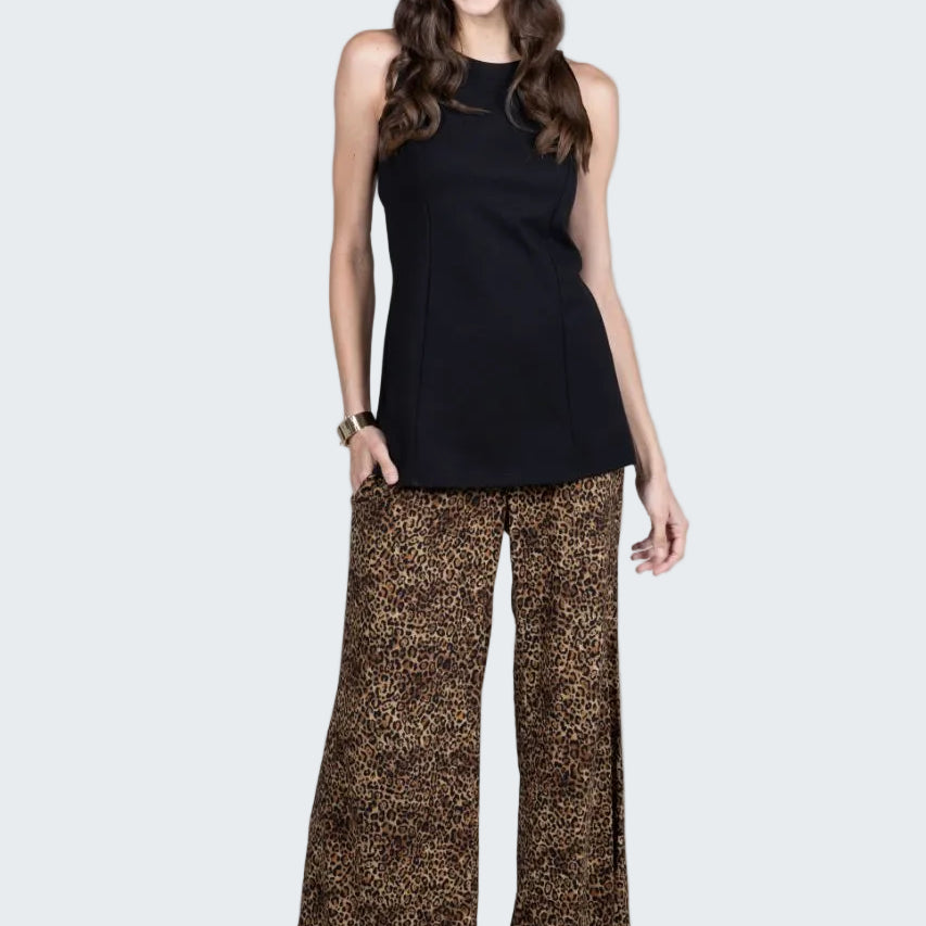 Woman wearing a black sleeveless top and patterned pants on a white background