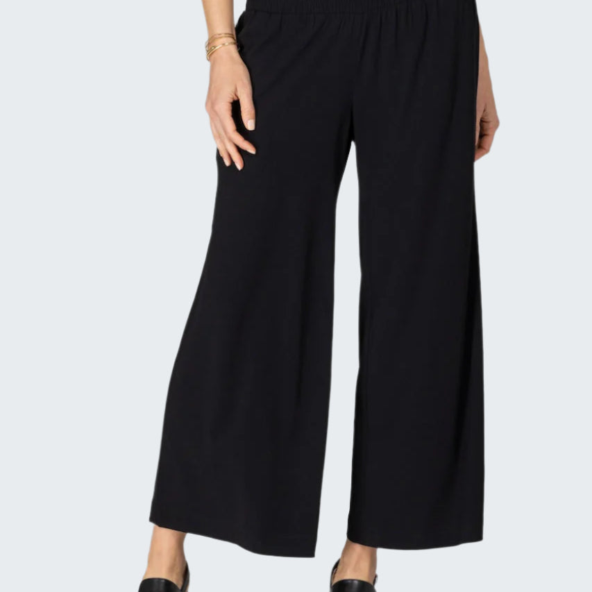 Person wearing black wide-leg pants on a white background