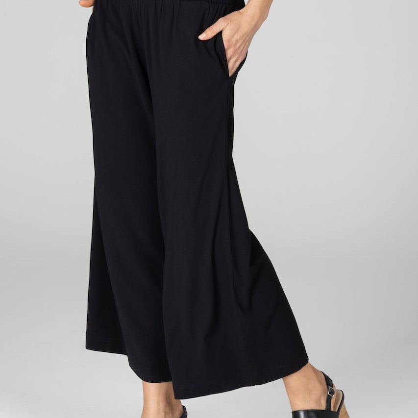 Person wearing black wide-leg pants on a white background