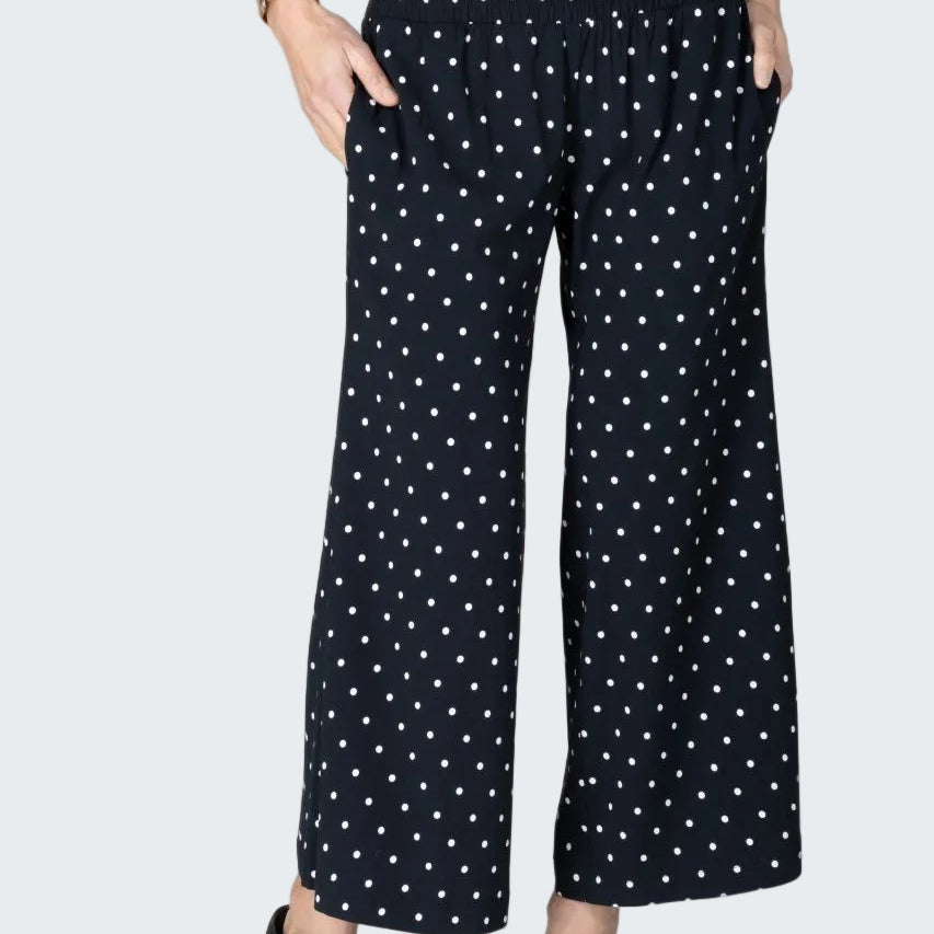 Person wearing black polka dot pants on a beige background