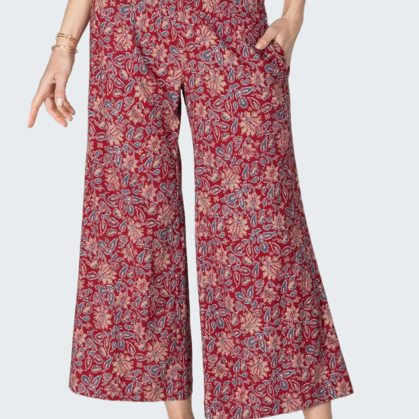 Person wearing red floral pants on a beige background