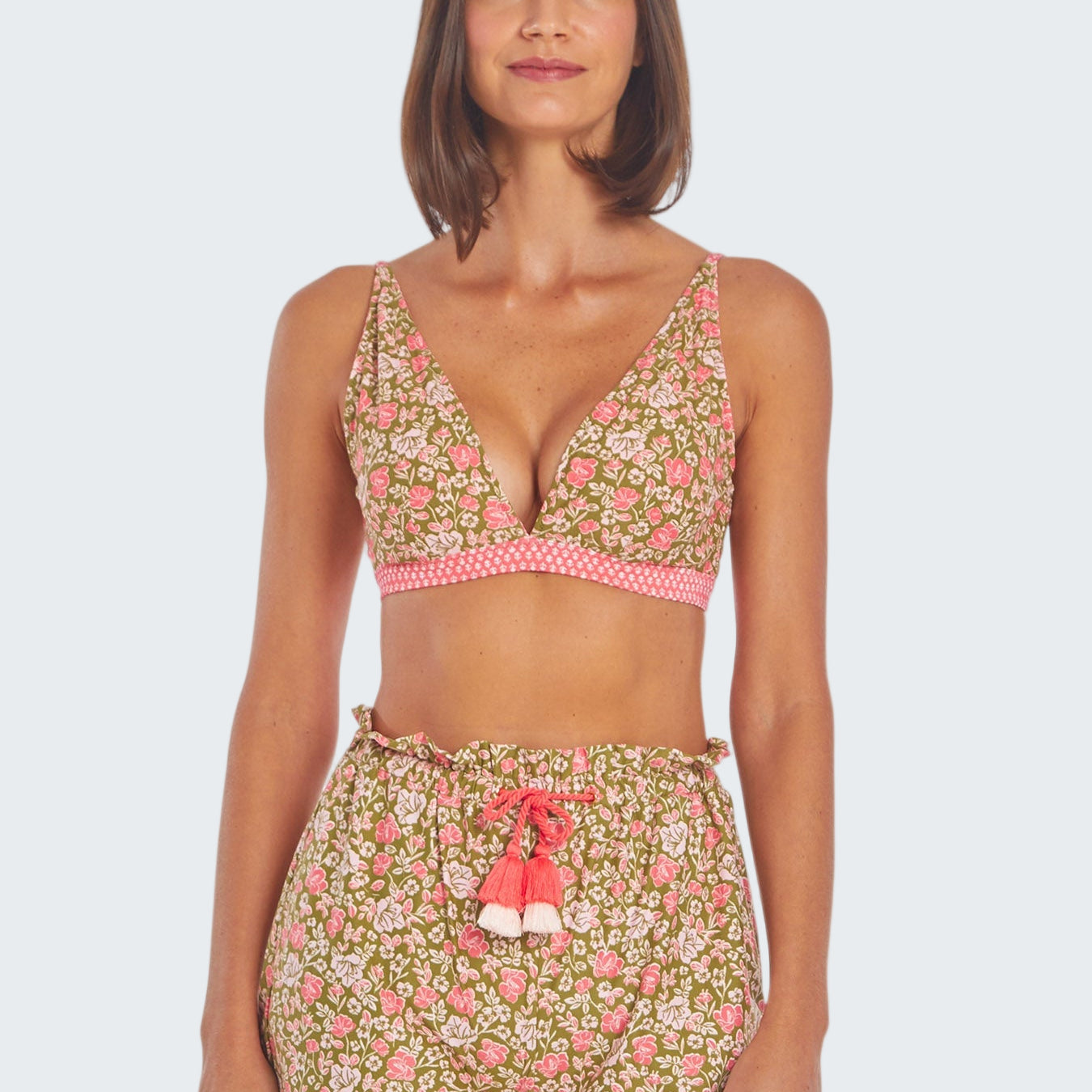 Woman wearing a floral two-piece swimsuit with pink accents on a white background