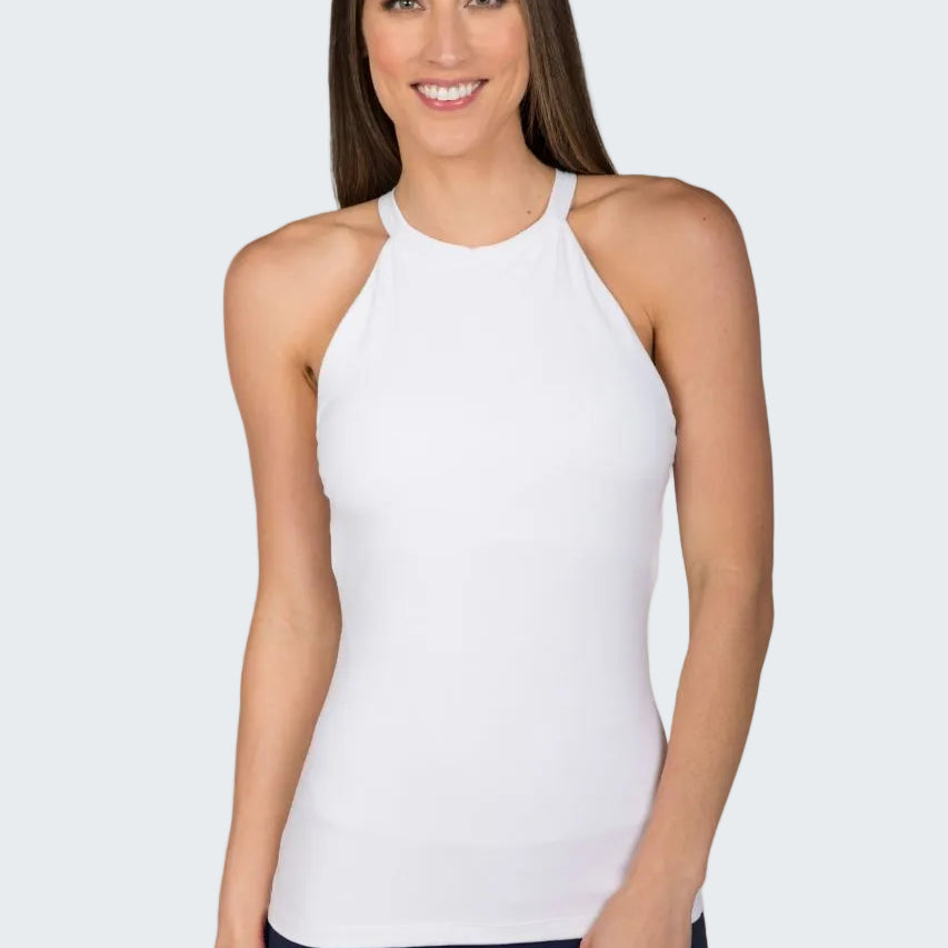 Woman wearing a white sleeveless top and dark pants against a beige background