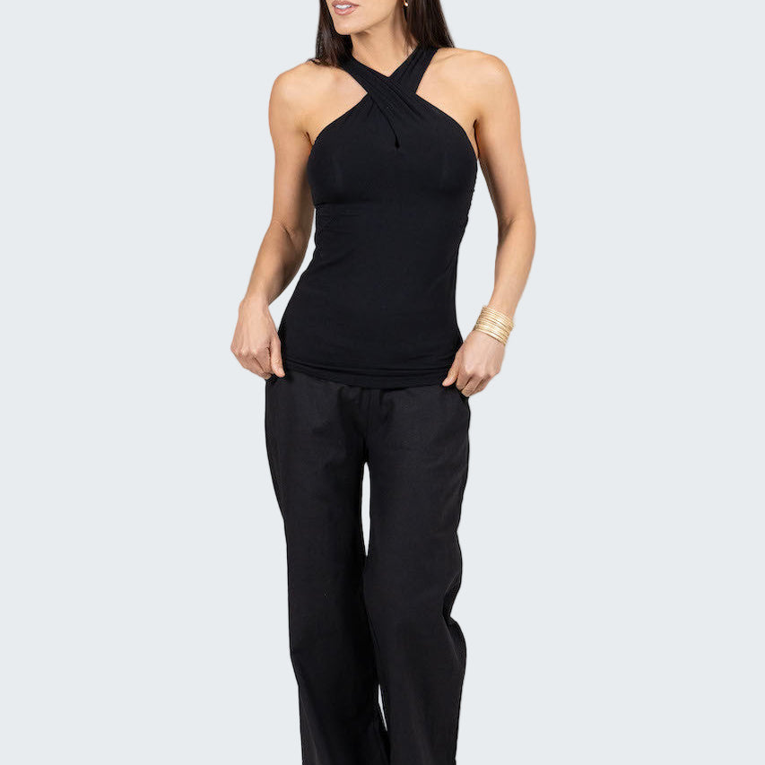 Woman wearing a black sleeveless top and black pants on a gray background