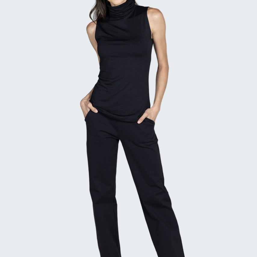 Woman wearing a black sleeveless top and pants on a gray background
