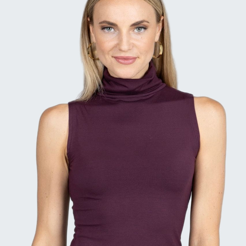 Woman wearing a sleeveless purple top against a gray background