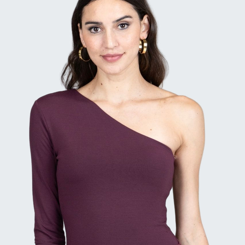 Woman wearing a one-shoulder purple dress against a gray background
