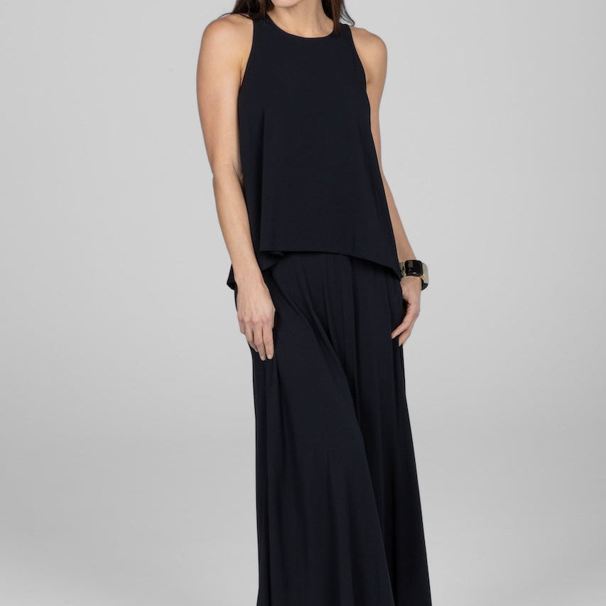 Woman wearing a black sleeveless top and wide-leg pants on a white background