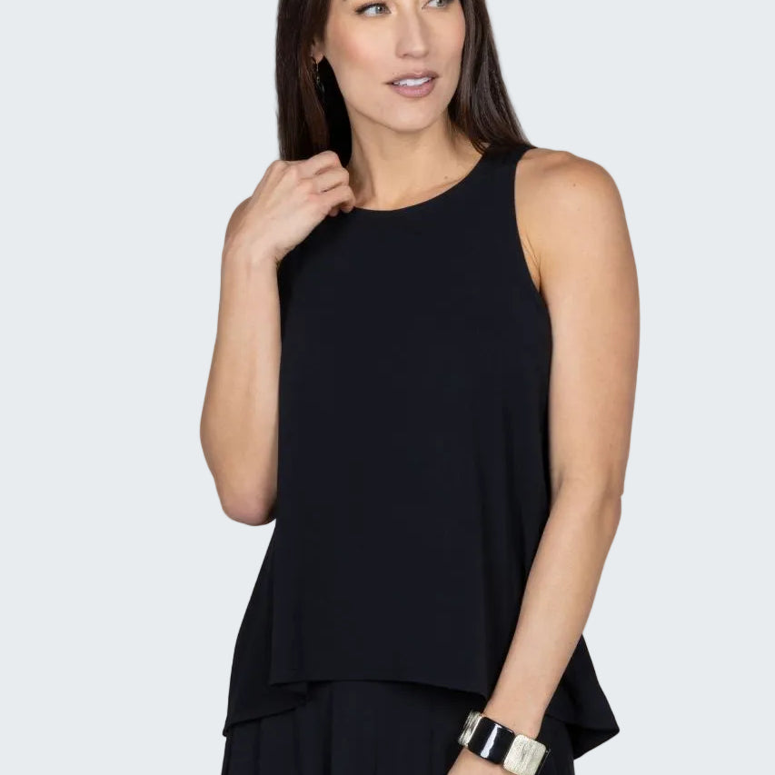 Woman wearing a black sleeveless top and dark pants against a beige background