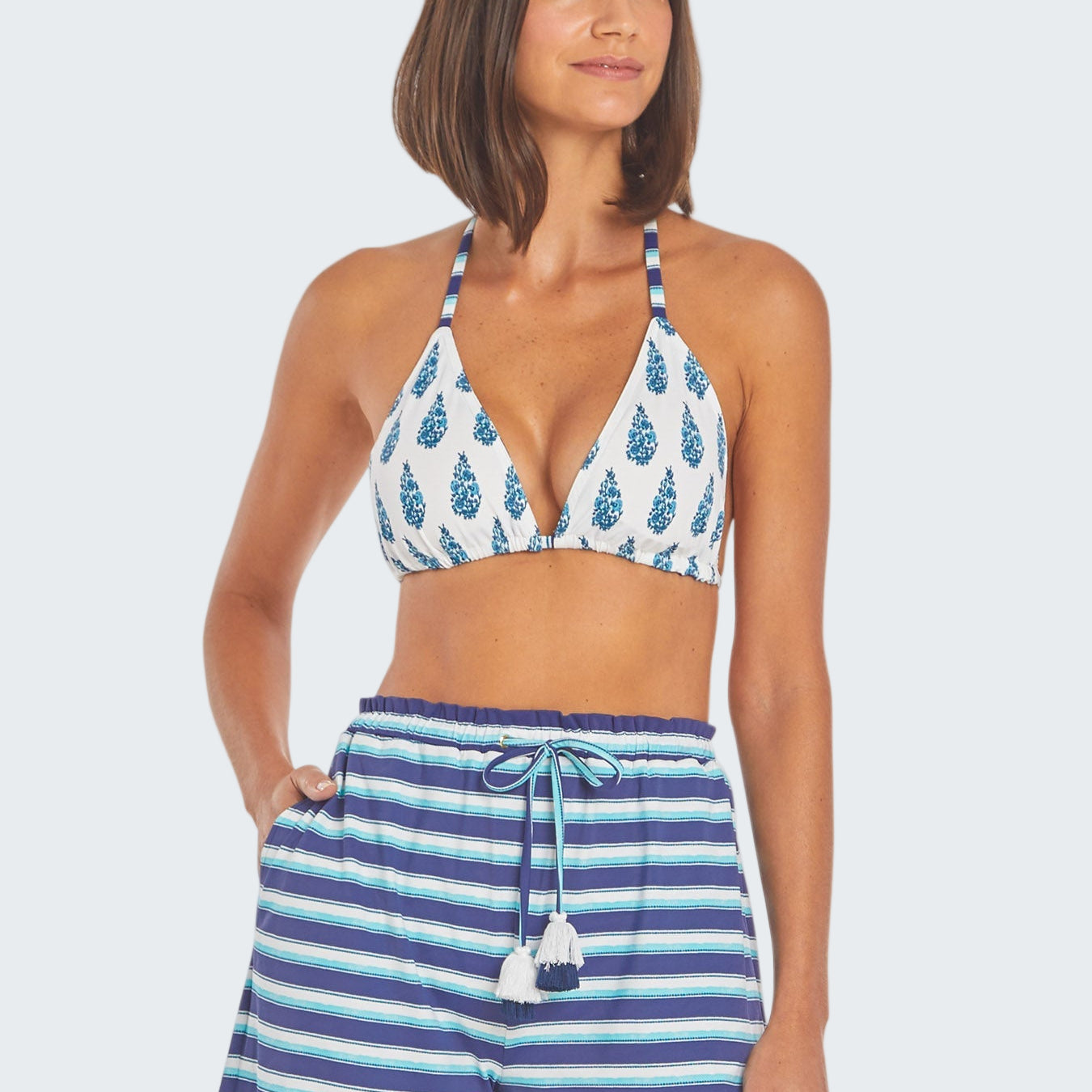 Woman wearing a blue and white patterned bikini with matching shorts on a white background