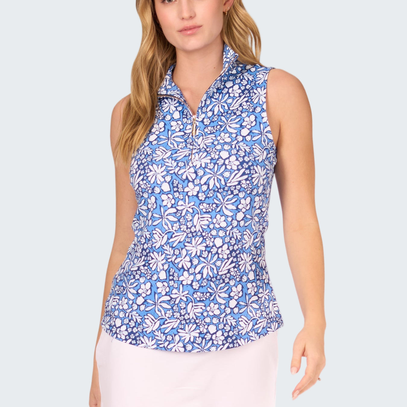 Woman wearing a blue floral sleeveless top and white skirt on a white background