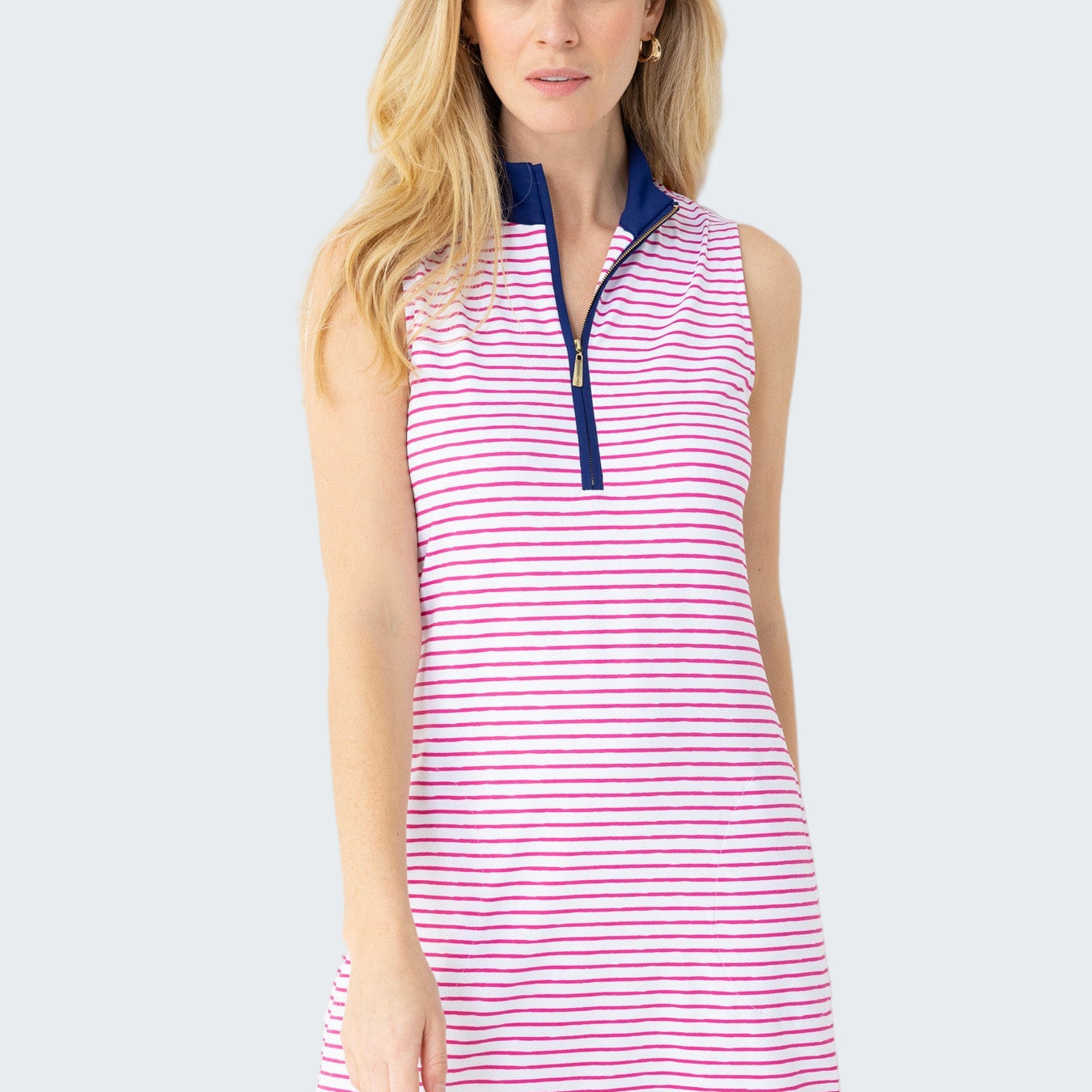Woman wearing a pink and white striped dress with a blue collar against a white background