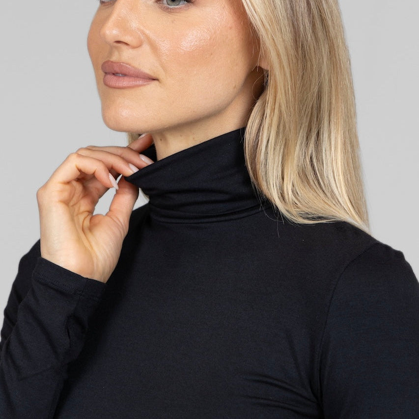 Woman wearing a black turtle neck sweater against a gray background