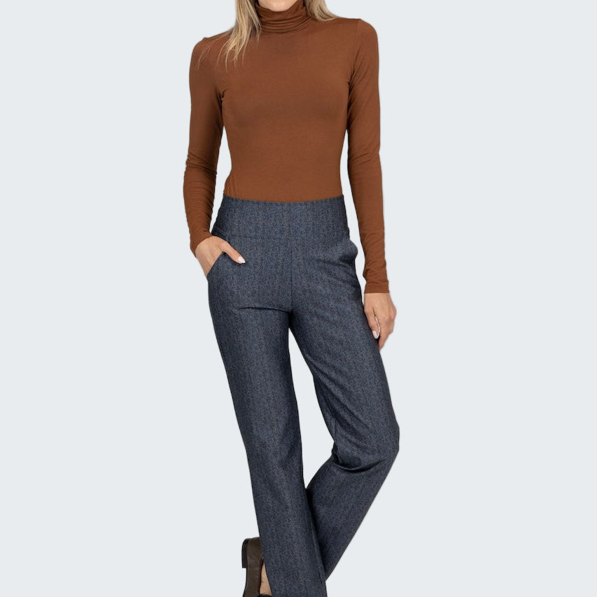 Woman wearing a brown turtleneck and gray pants on a white background