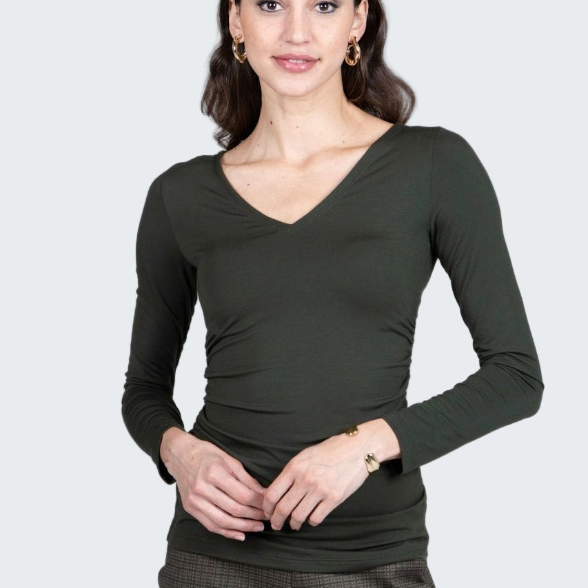 Woman wearing a dark green long-sleeve top and plaid pants on a gray background