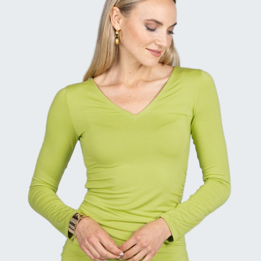 Woman wearing a green long-sleeve top on a gray background