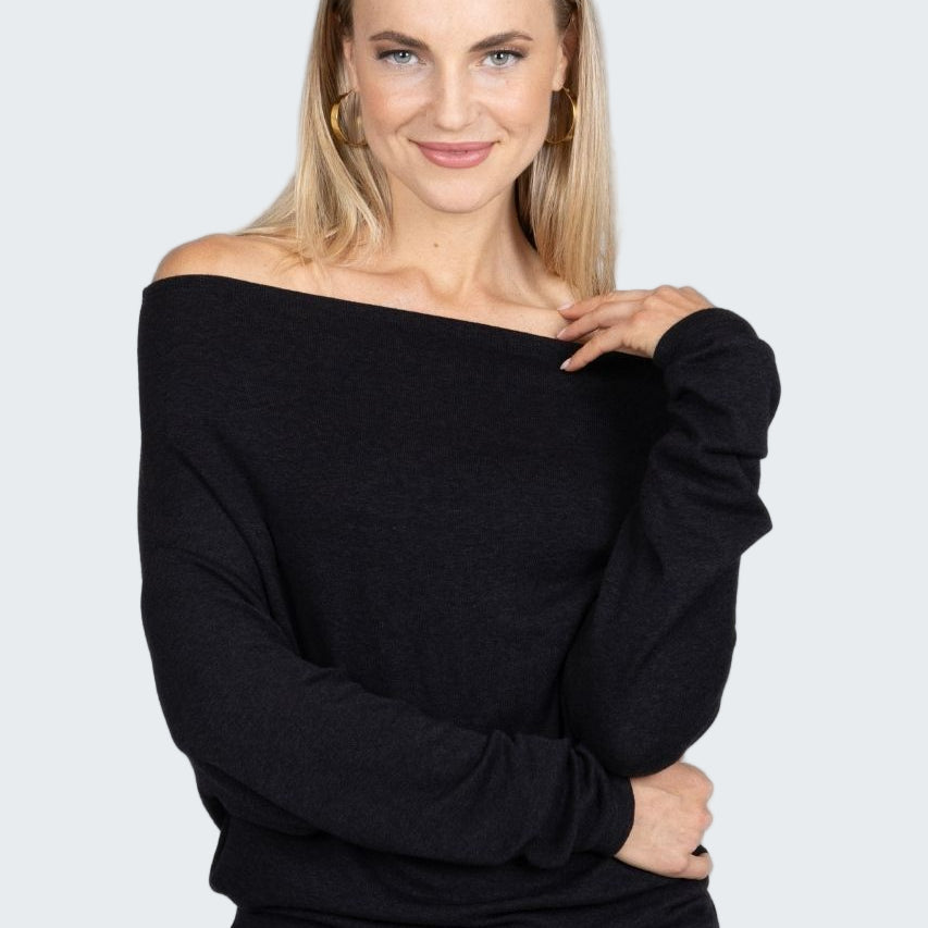 Woman wearing a black off-shoulder top against a plain background