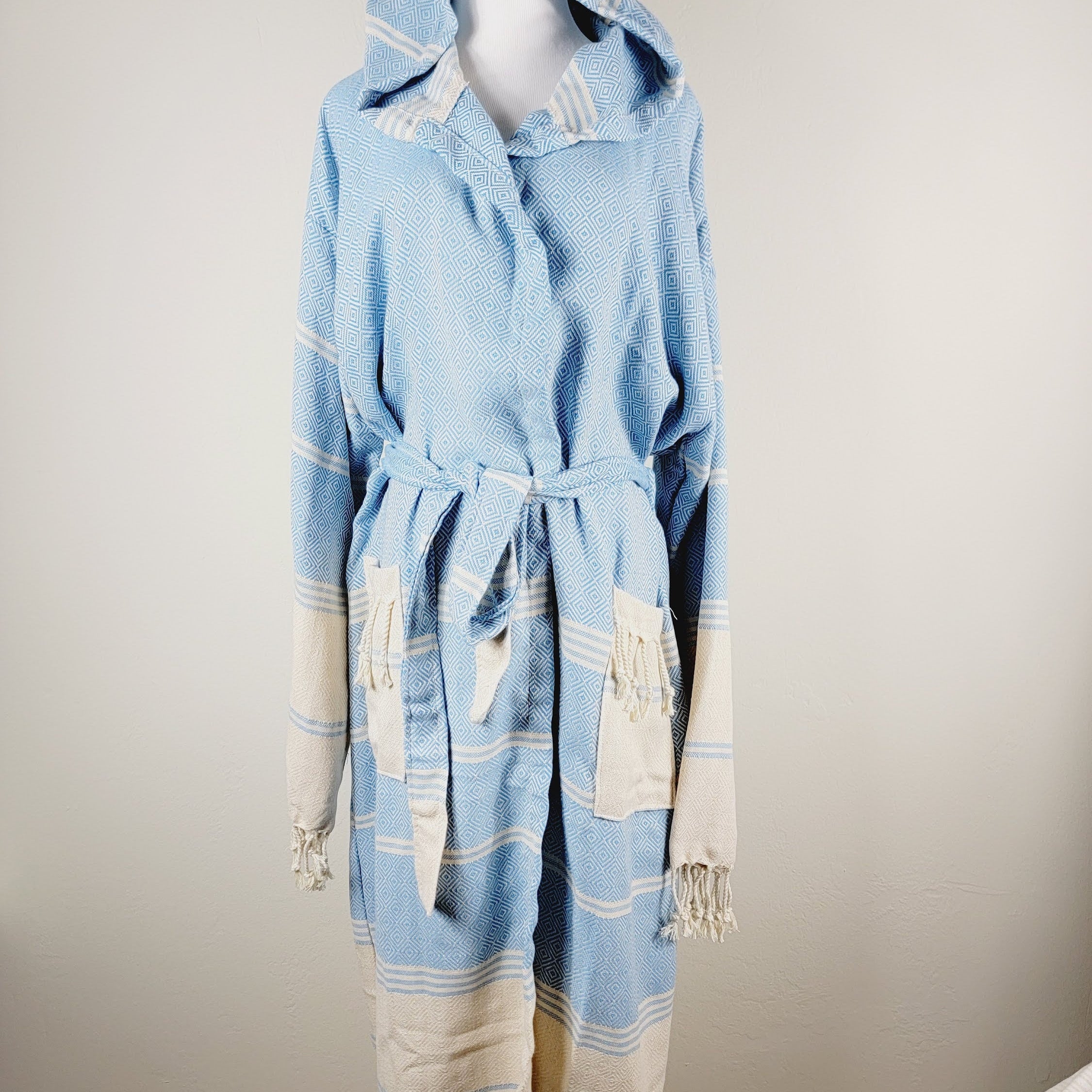 Light blue and beige robe with hood on a mannequin against a plain background