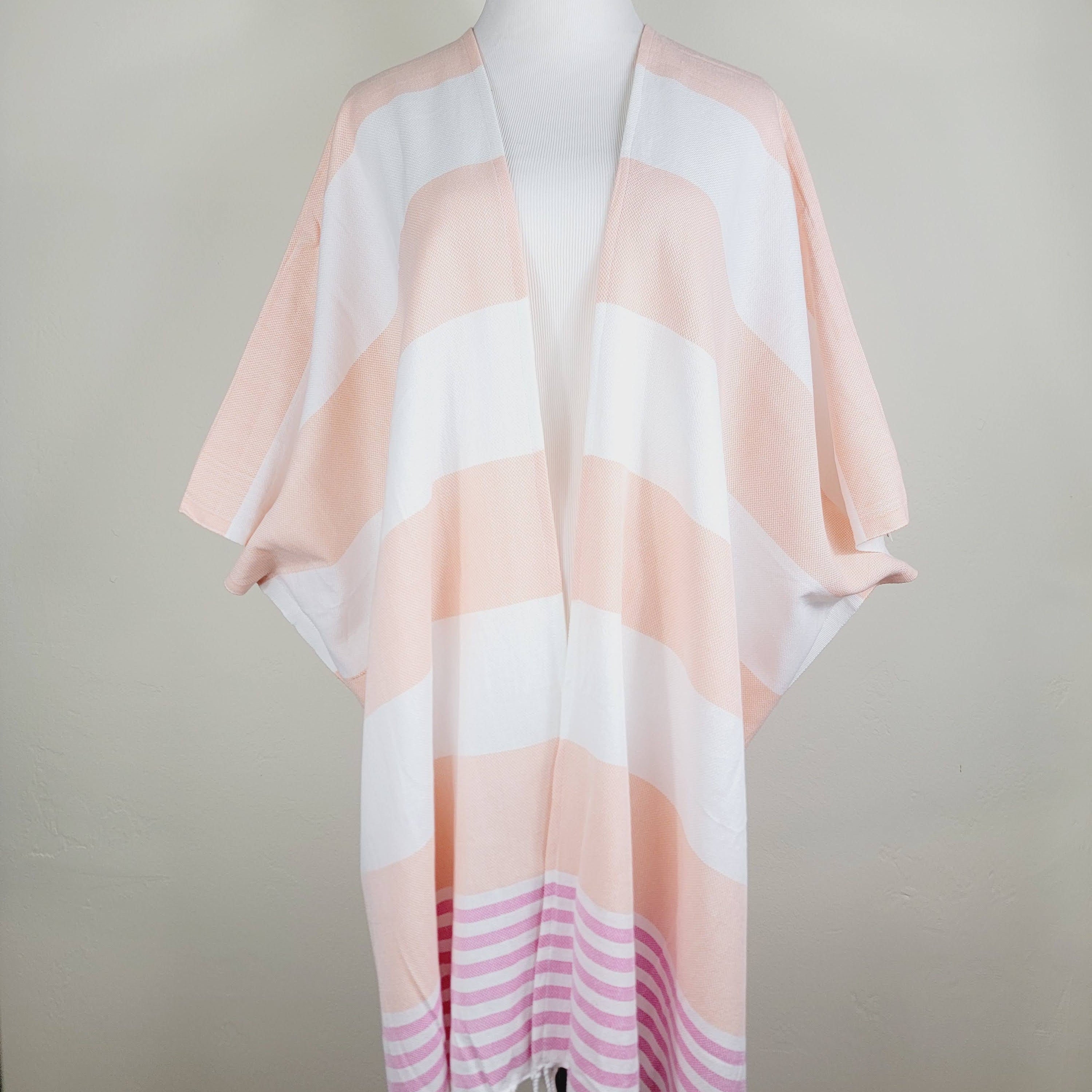 Mannequin wearing a light pink and white striped scarf with fringe on a plain background