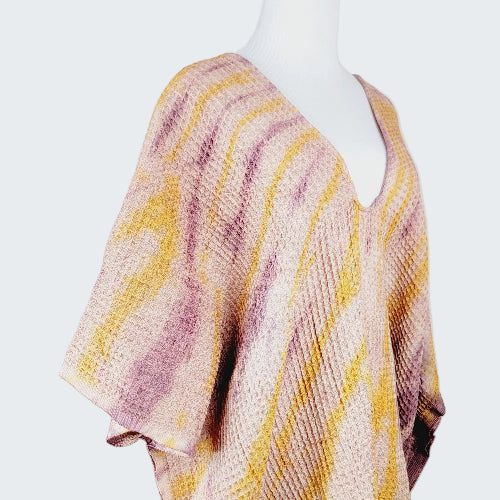 Mannequin wearing a pink and yellow patterned poncho against a plain background