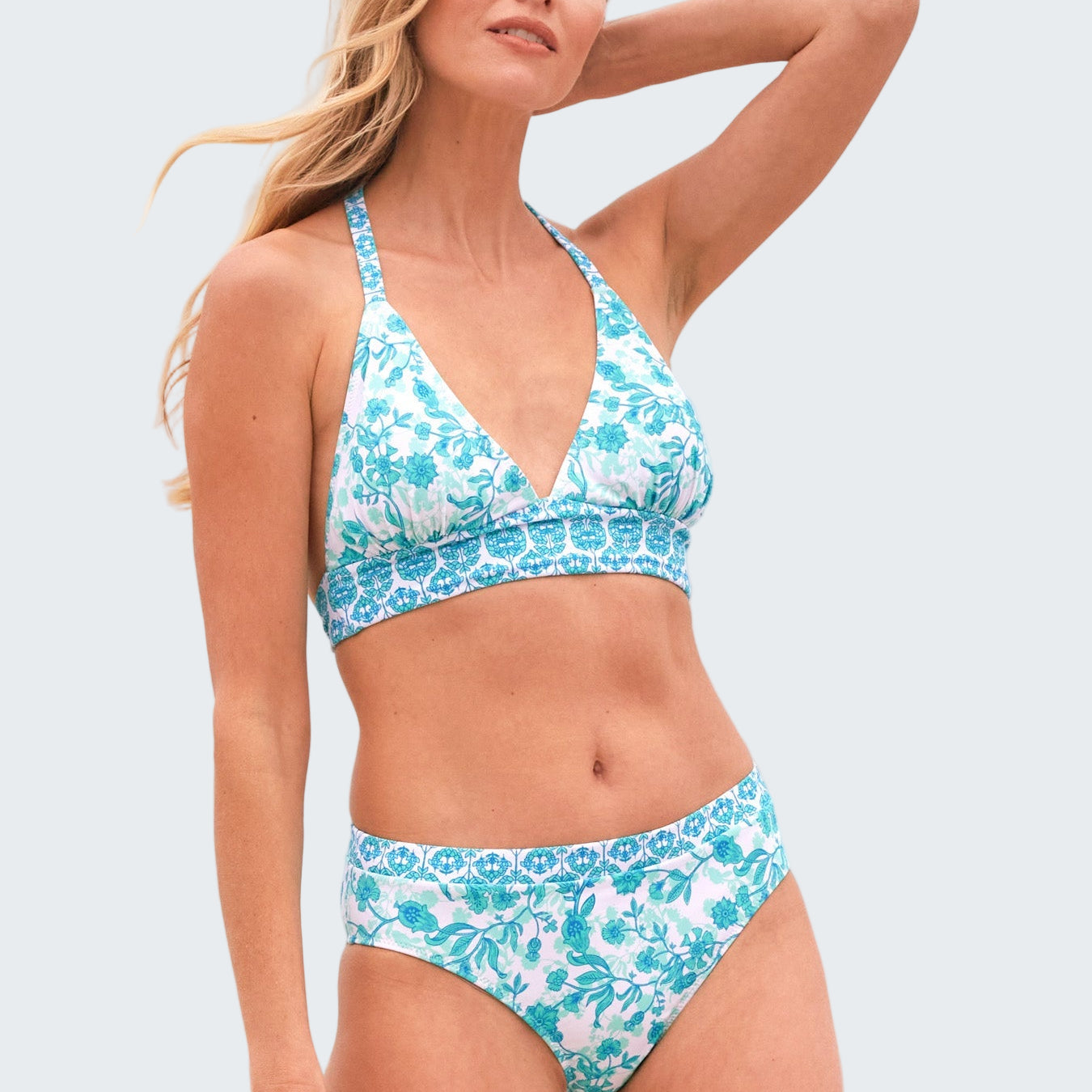 Woman wearing a blue floral bikini set with a beach background