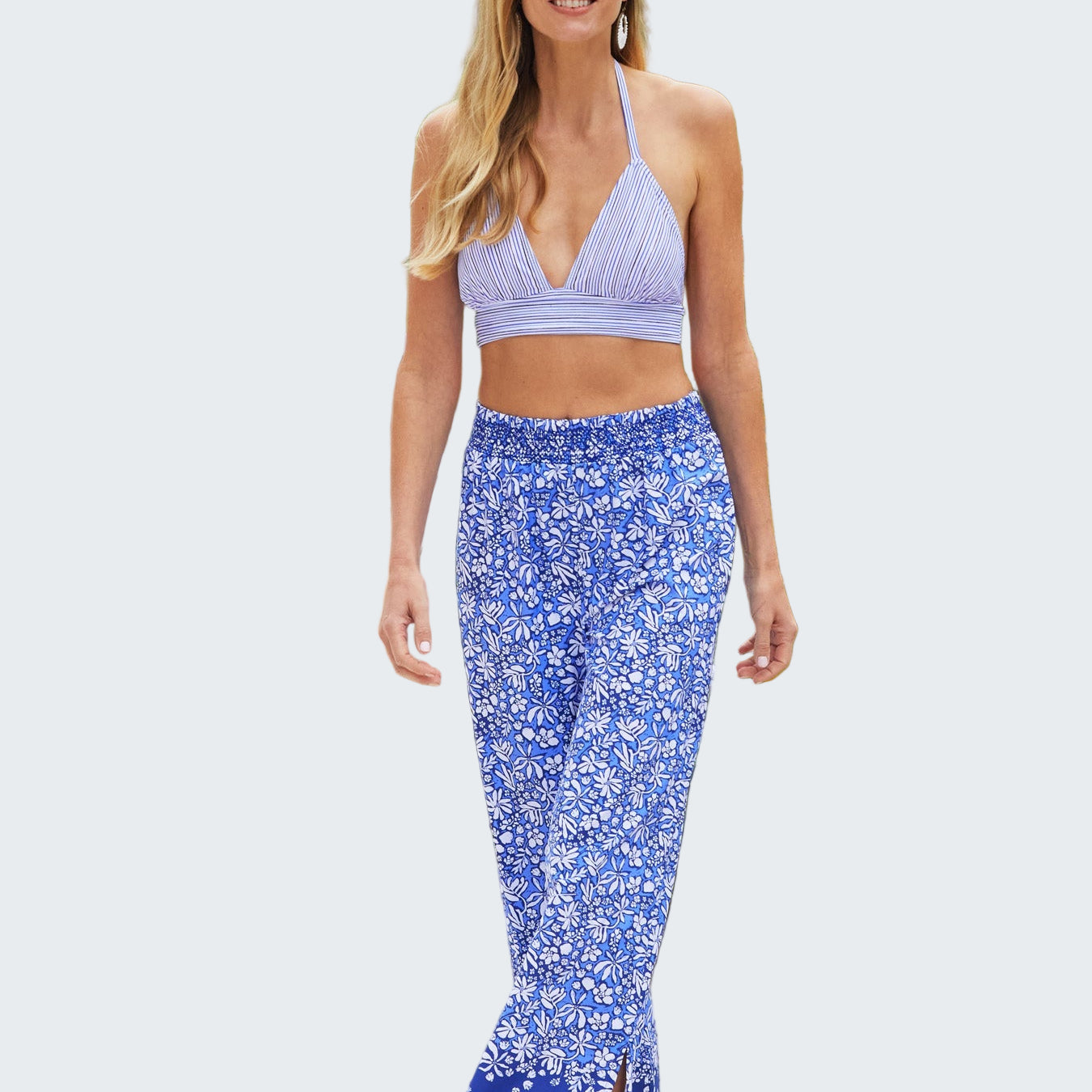 Woman in a blue floral dress standing on a sandy path with greenery in the background