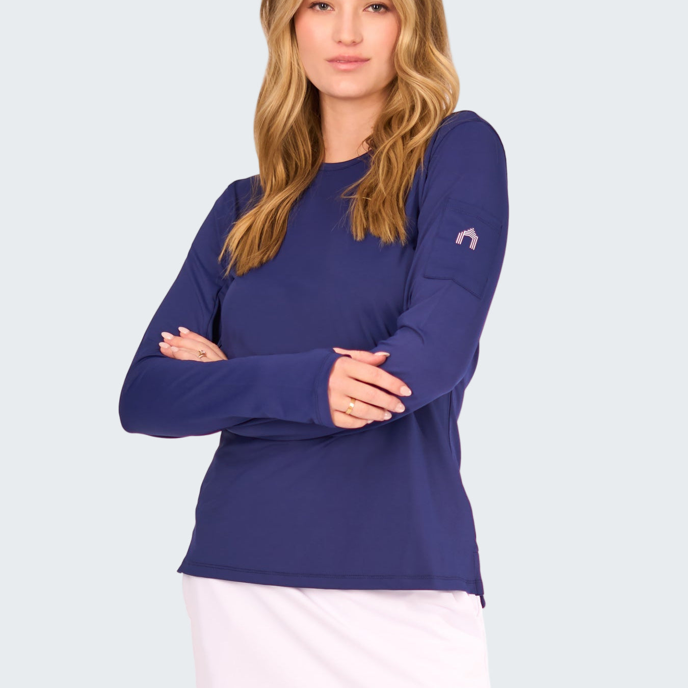 Woman wearing a blue long-sleeve top and white skirt on a white background
