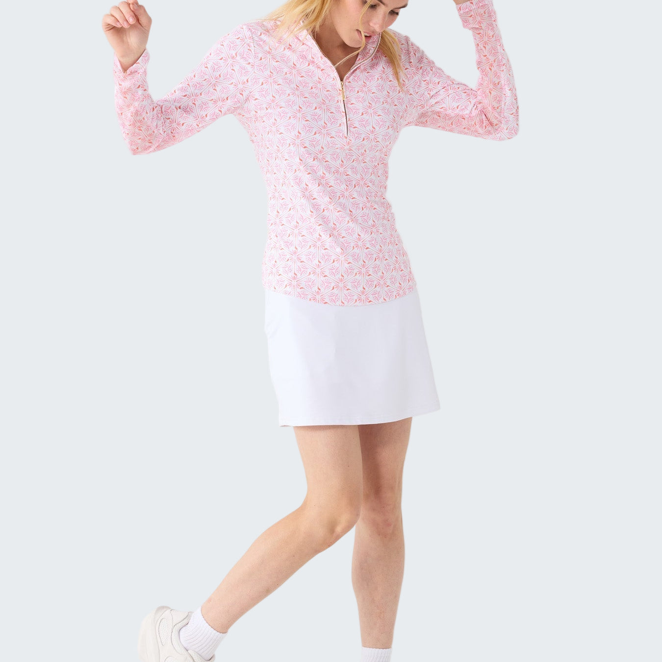 Woman wearing a pink long-sleeve top and white skirt on a white background