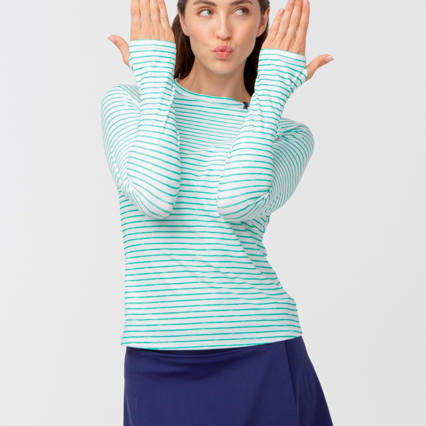 Woman wearing a striped long-sleeve shirt and blue skirt on a light gray background