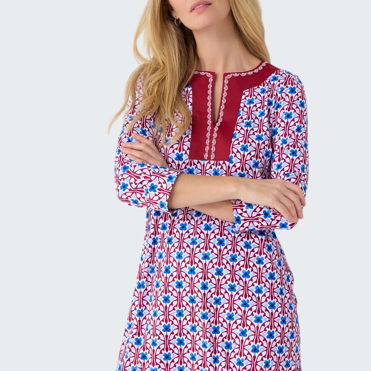 Woman wearing a patterned dress with red, white, and blue design on a plain background