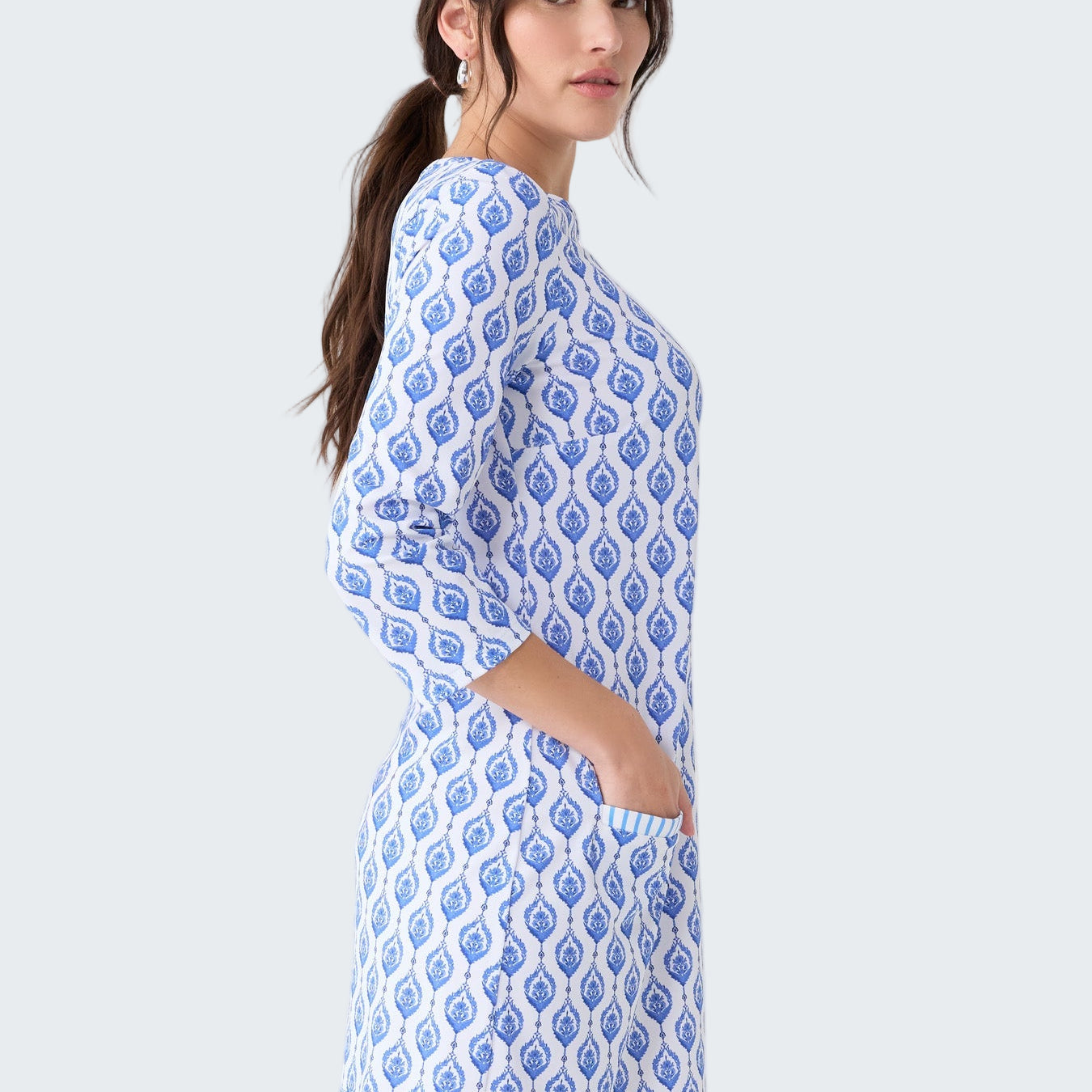 Woman wearing a blue and white patterned dress on a light gray background