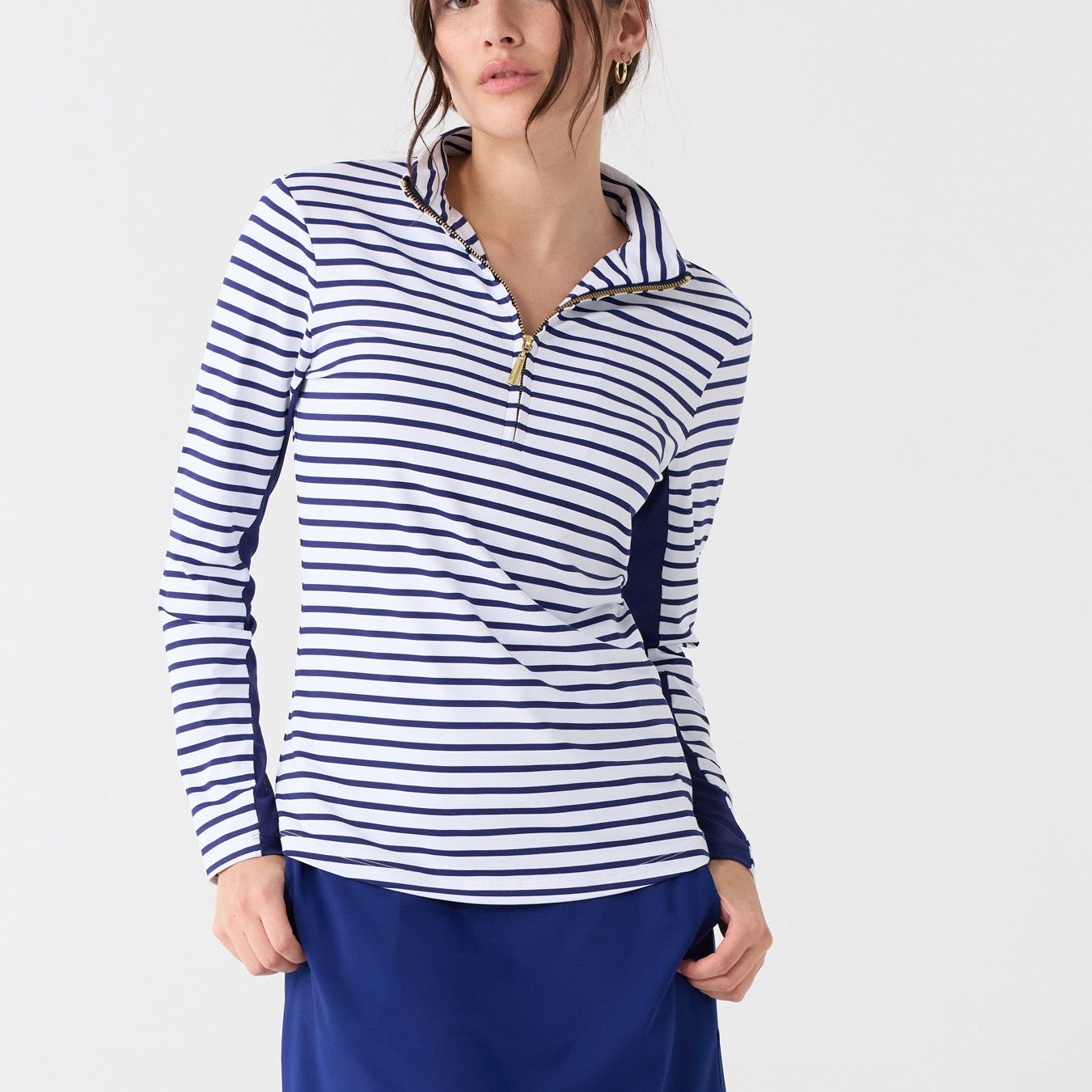 Woman wearing a striped long-sleeve top and blue skirt on a white background