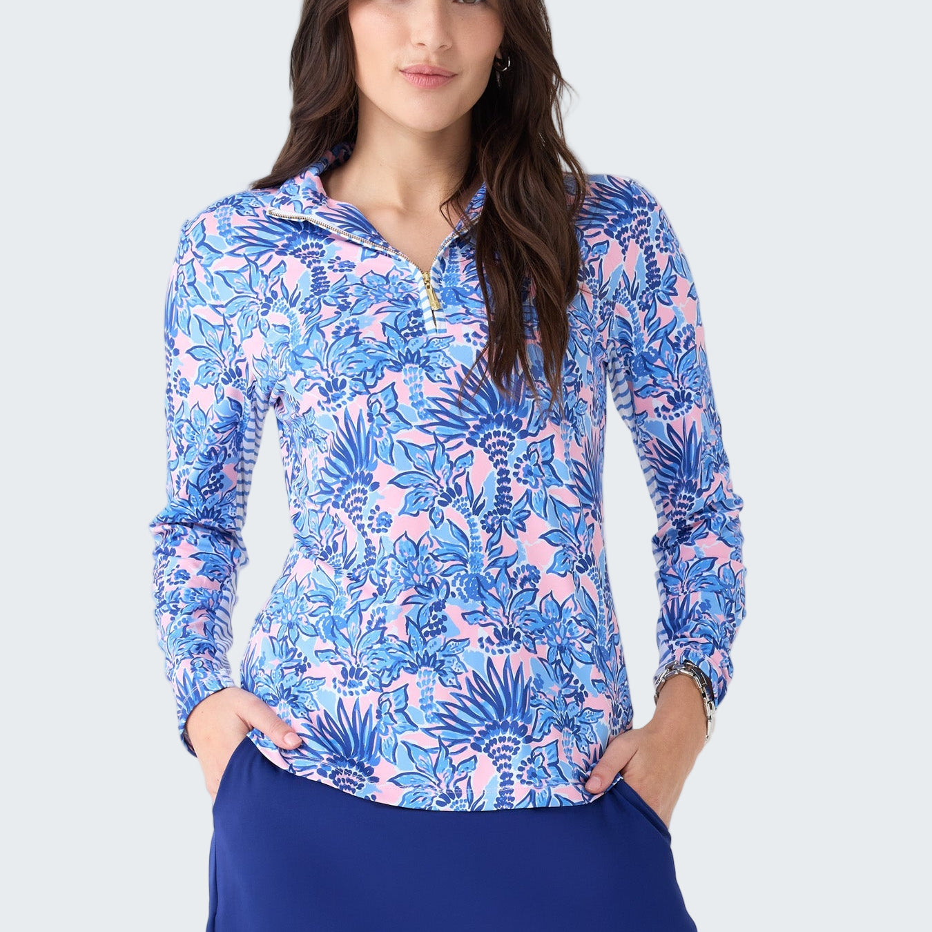 Woman wearing a blue and pink floral long-sleeve top and blue skirt on a white background