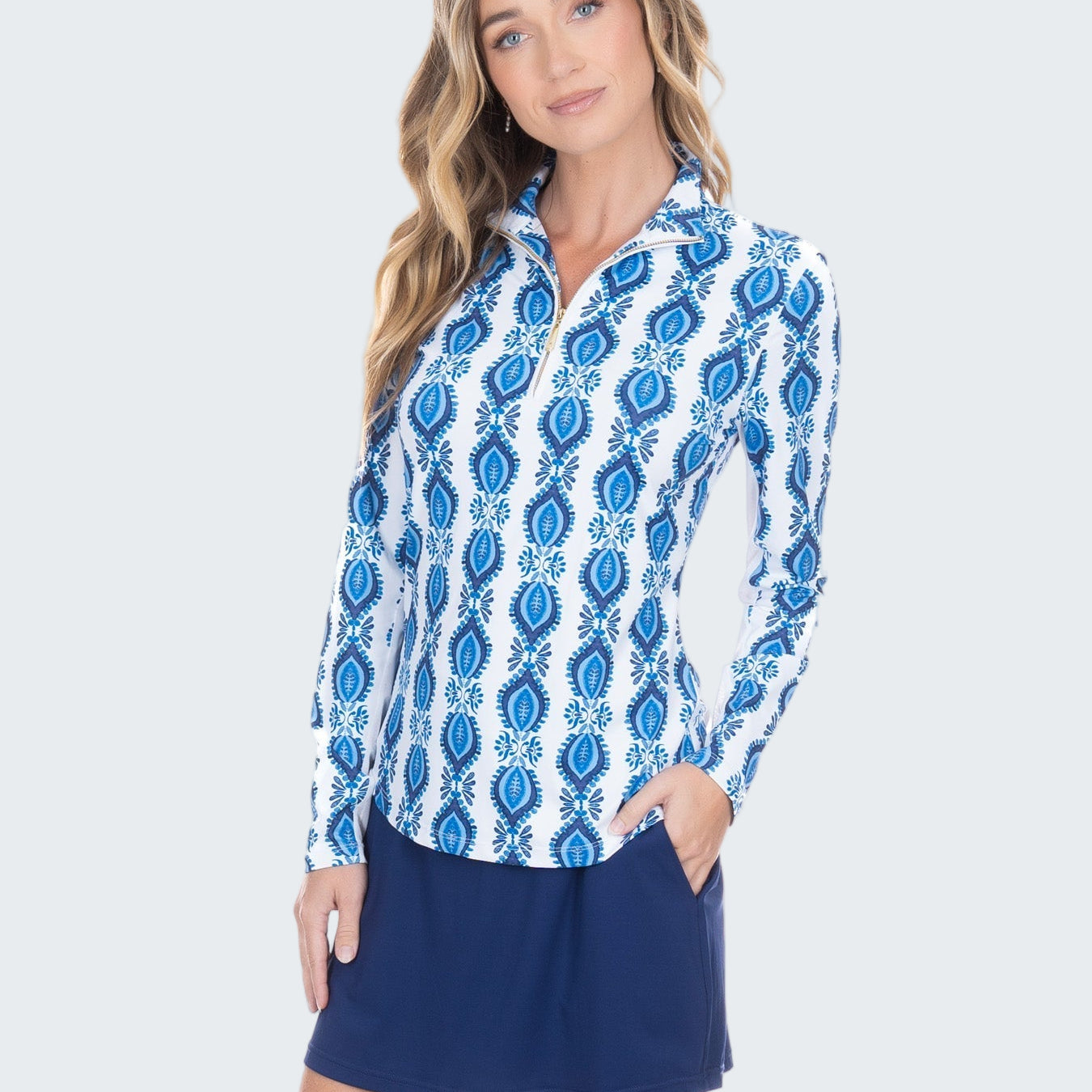 Woman wearing a blue and white patterned shirt with a navy skirt on a white background