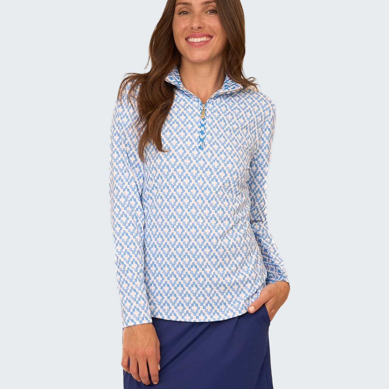 Woman wearing a blue and white patterned long-sleeve shirt with a navy skirt on a white background