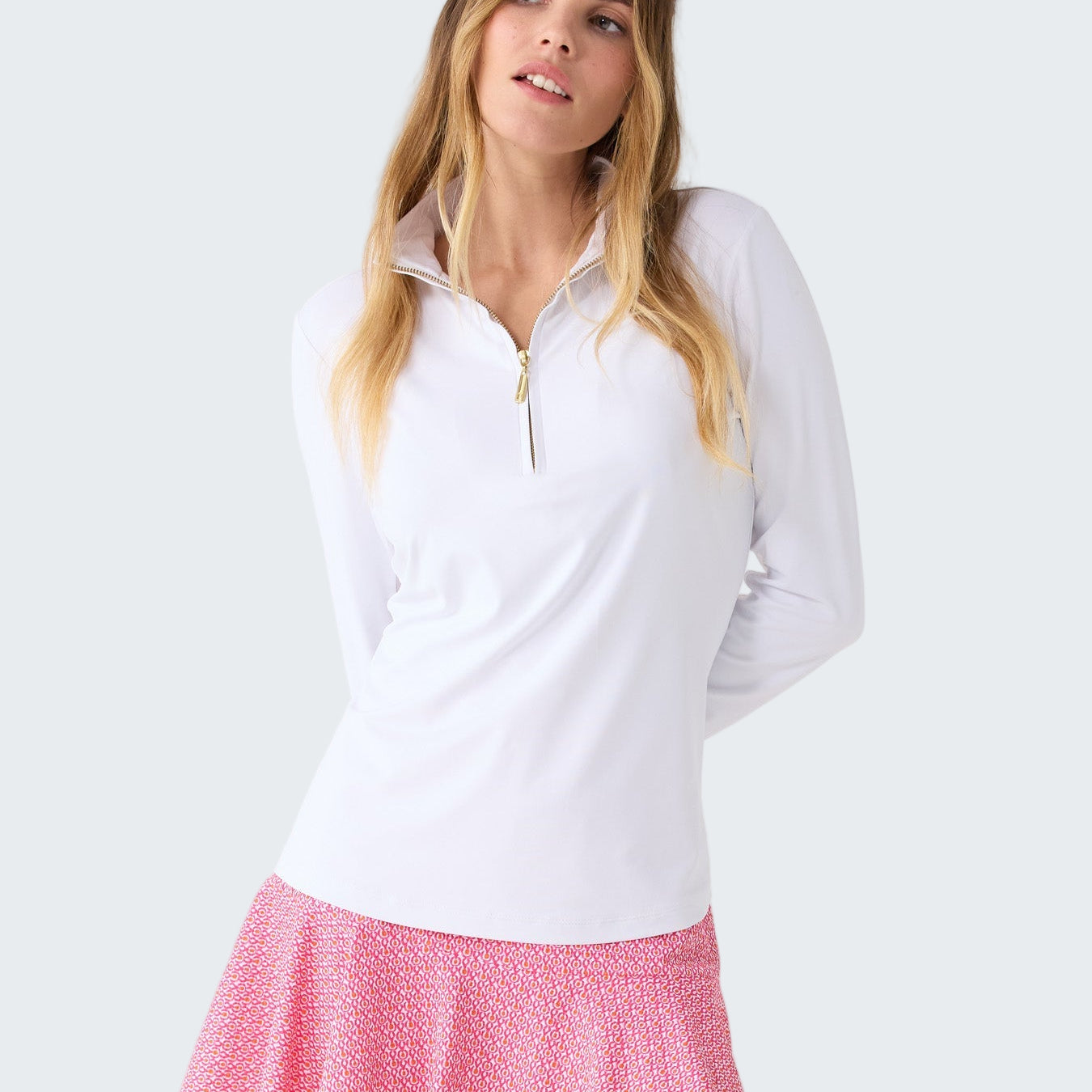 Woman wearing a white long-sleeve top and pink skirt on a white background