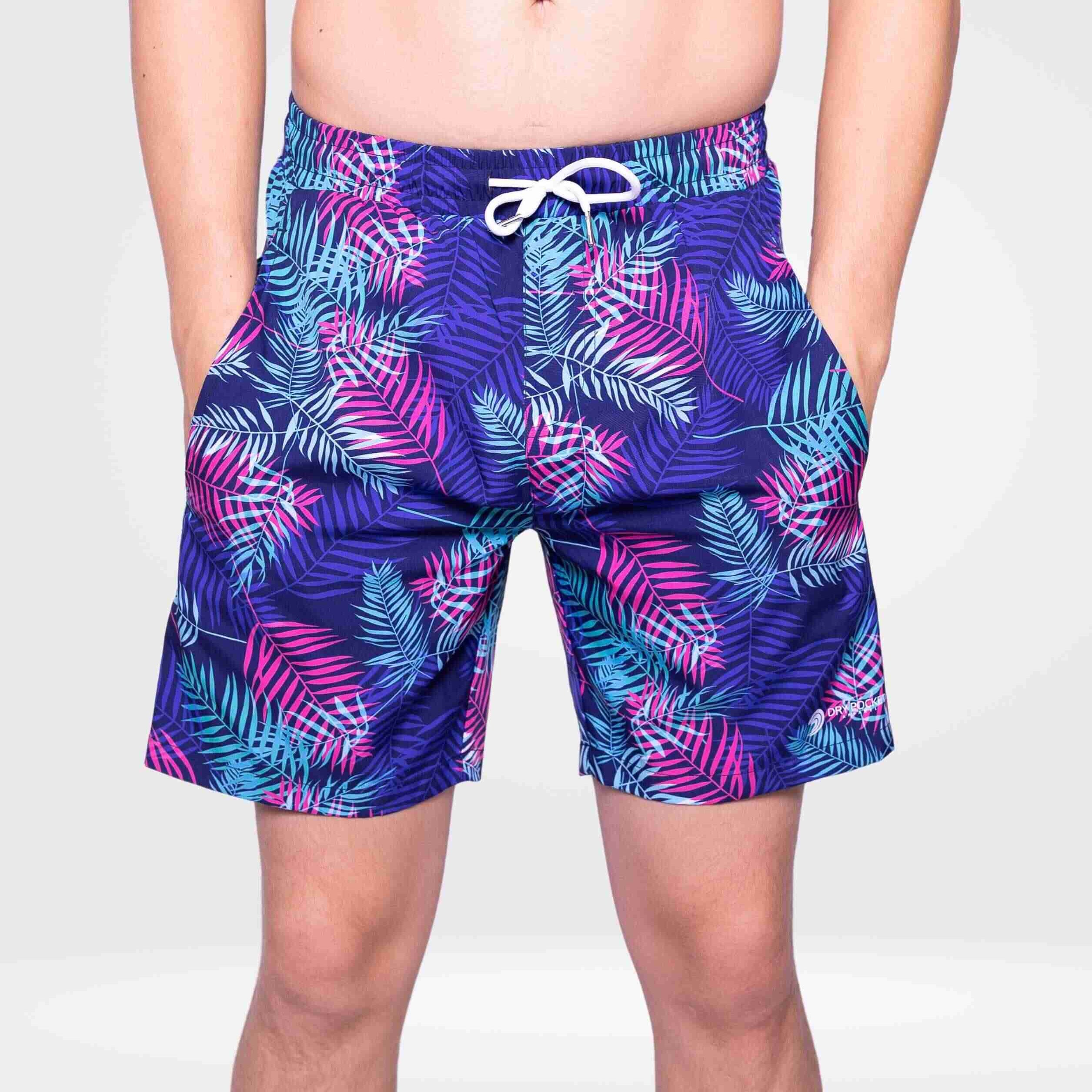 Person wearing purple tropical leaf patterned shorts on a white background