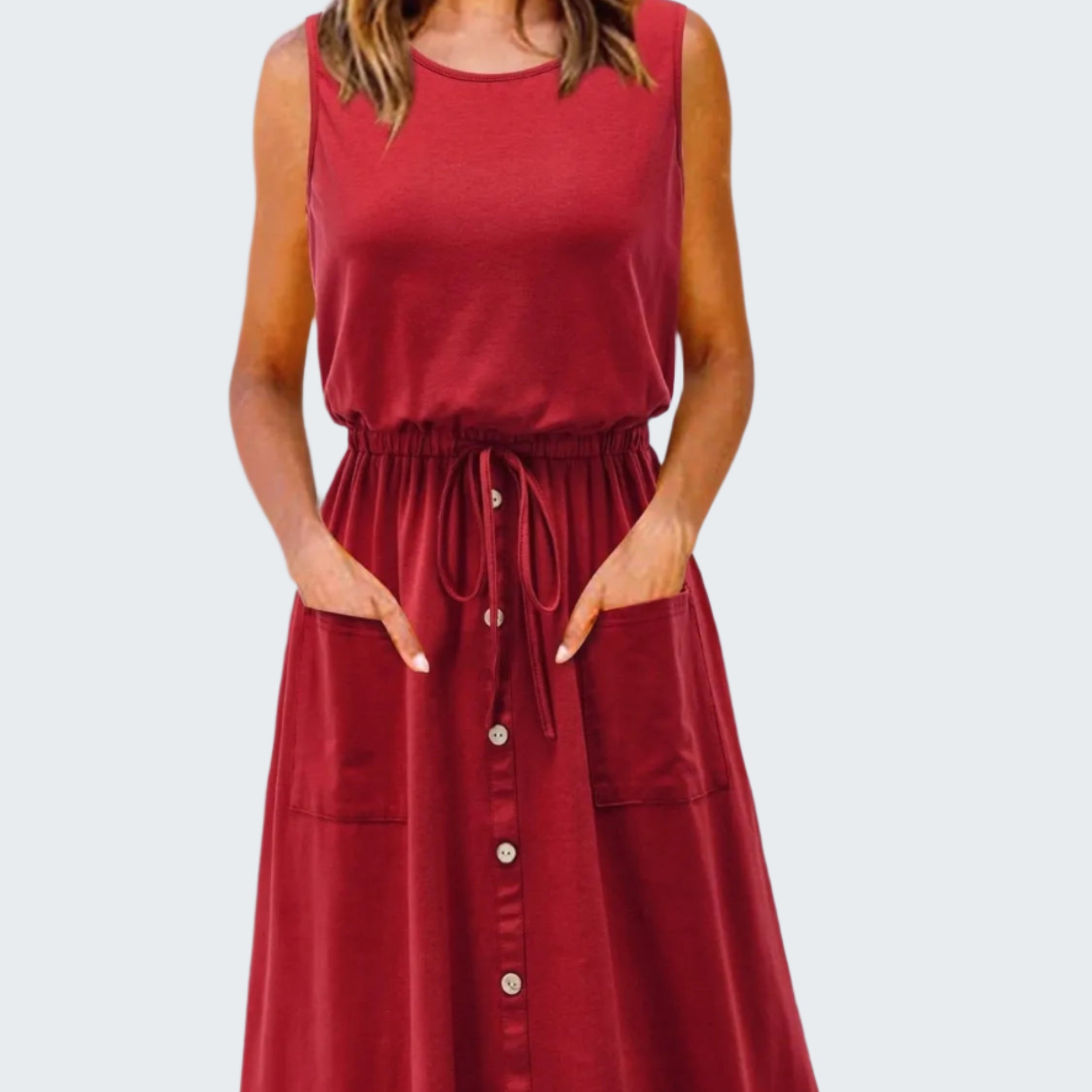 A model wearing a red sleeveless knee-length dress with a round neckline, drawstring waist, and front pockets.