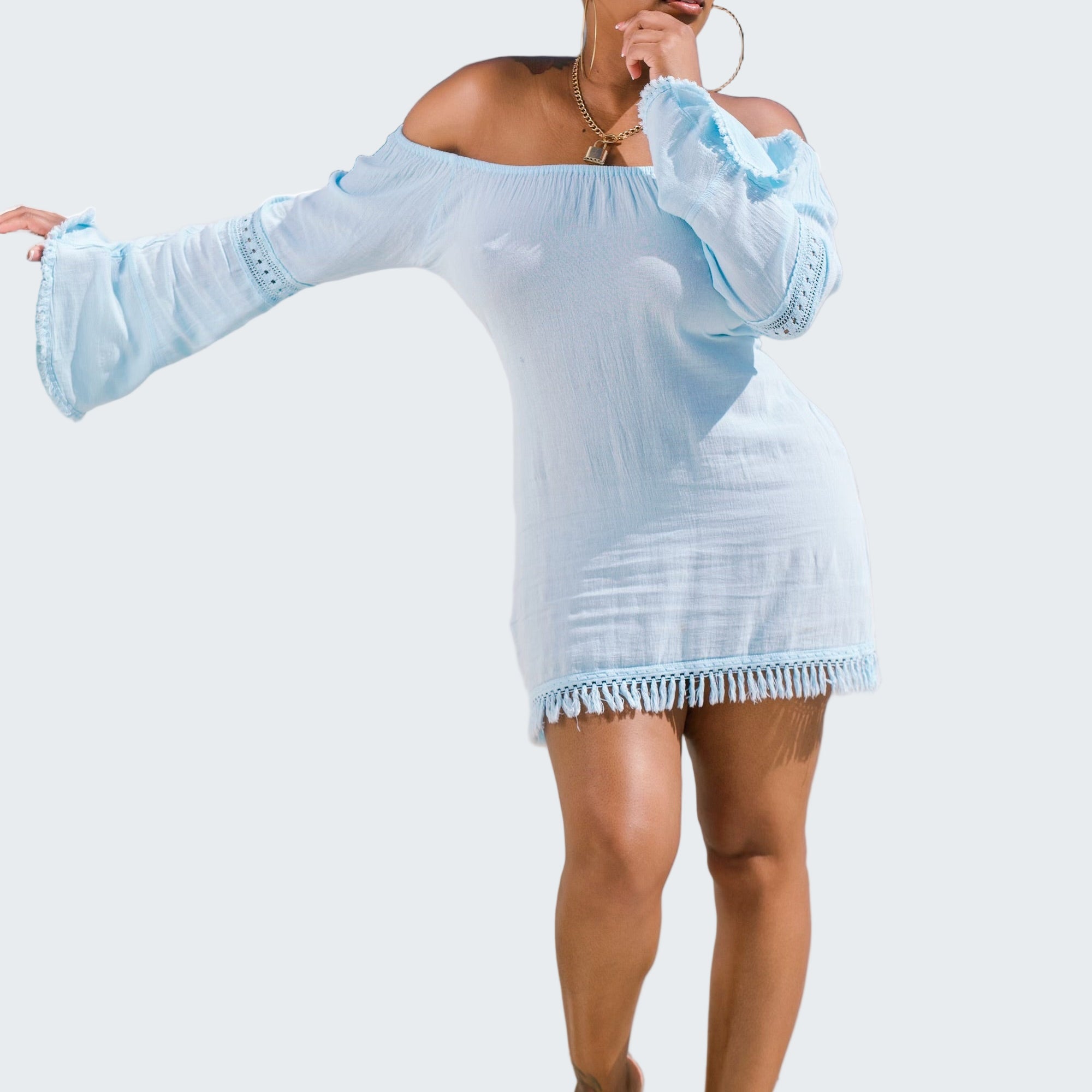 Woman in a light blue dress standing on a rooftop with a cityscape background