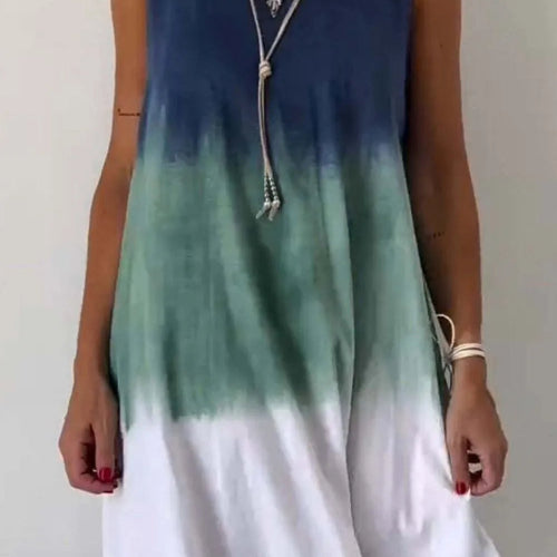 A sleeveless mini tank dress with tie-dye patterns in blue and green shades on a white background.