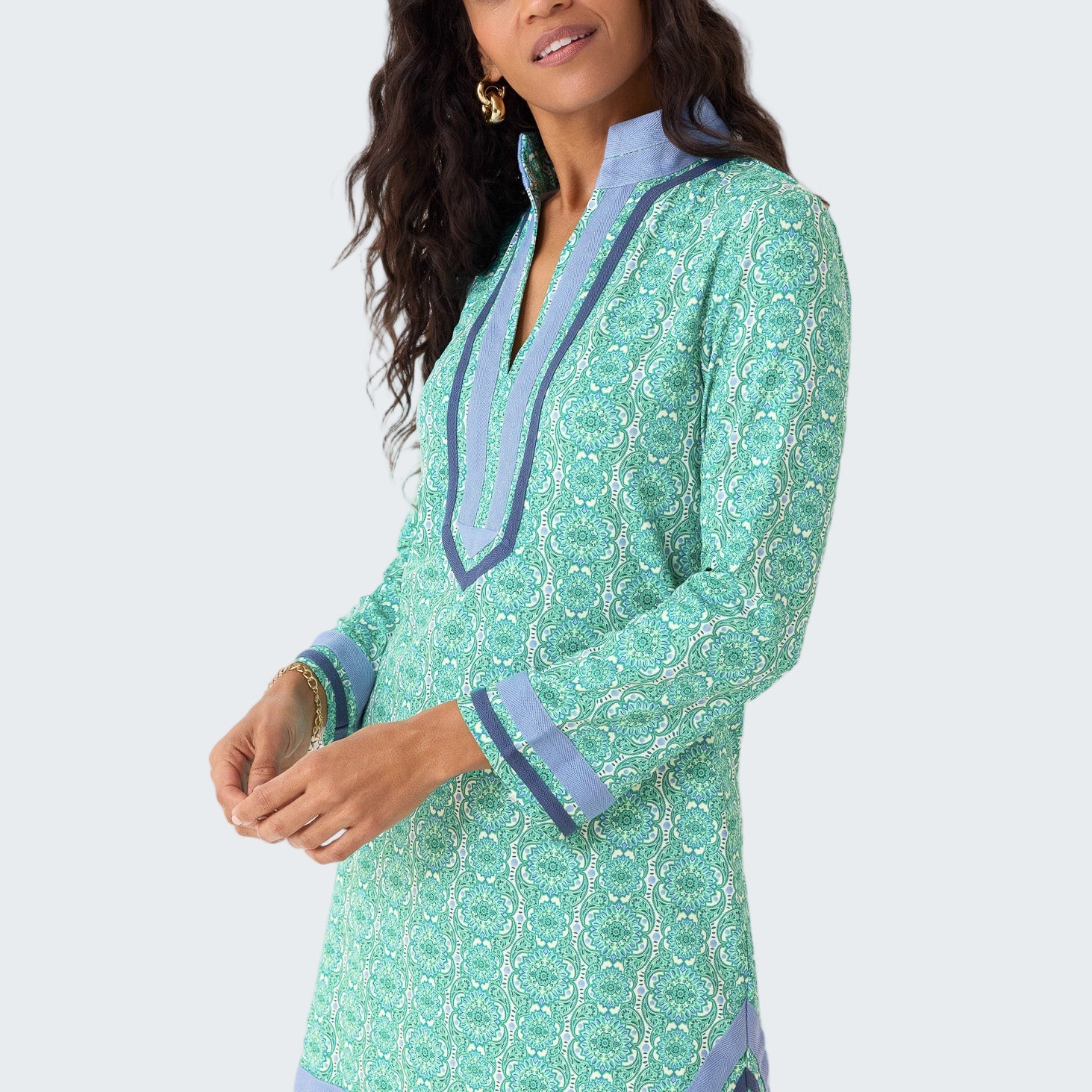 Woman wearing a green patterned dress with blue accents on a white background