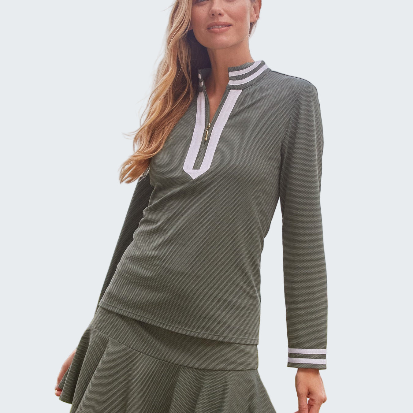 Woman wearing a green dress with white trim by the ocean