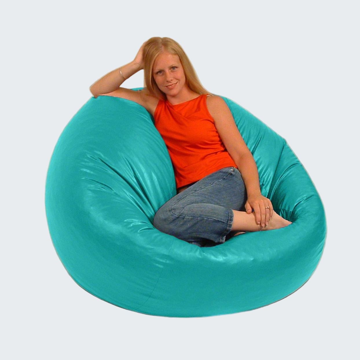 Woman sitting in a large teal bean bag chair indoors.