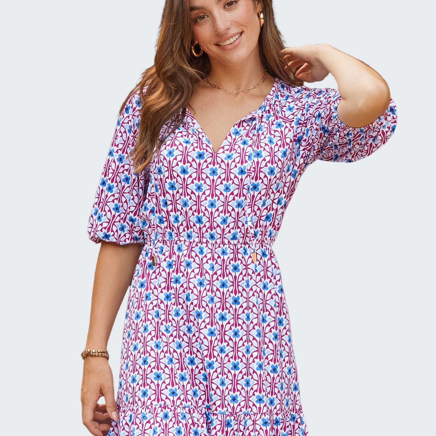 Woman wearing a patterned dress standing in front of a green door.