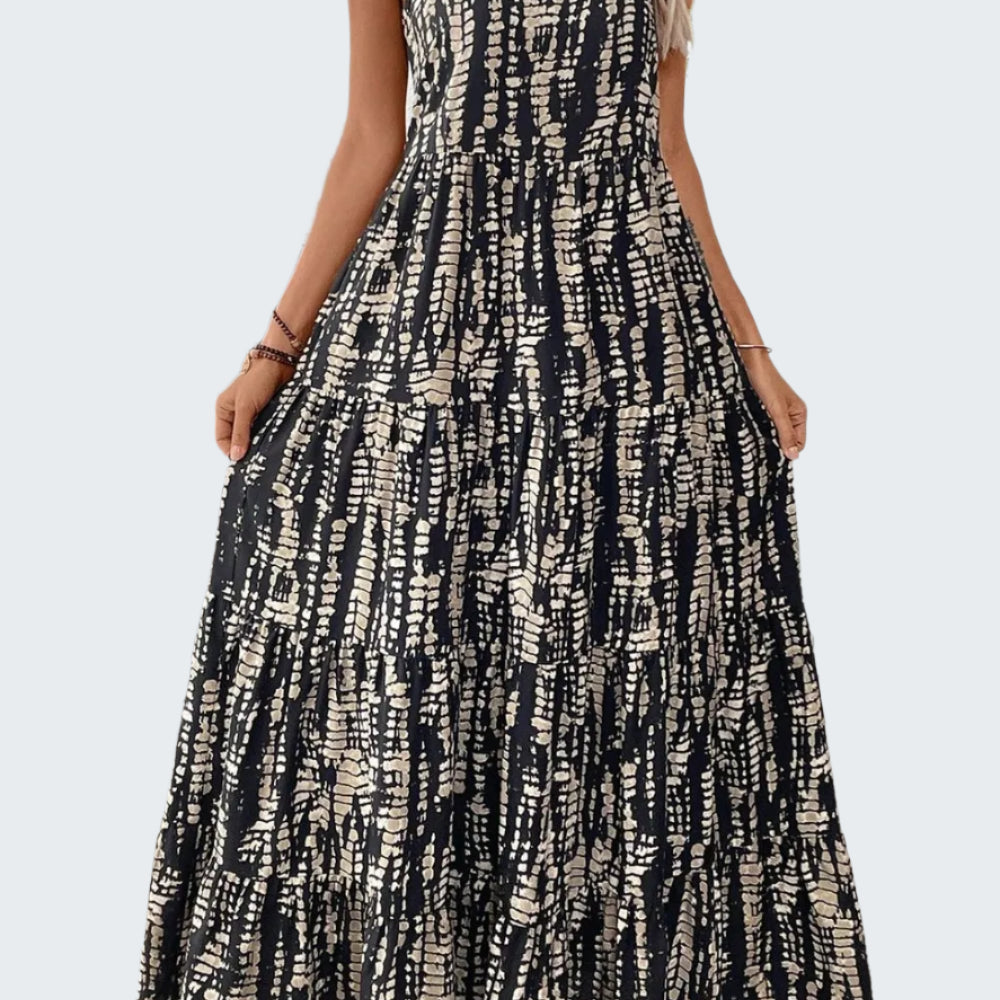 A model wearing a sleeveless, scoop neck, maxi length dress with a geometric print.