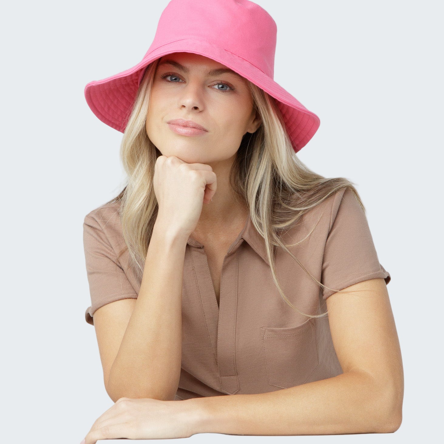 Woman wearing a pink bucket hat against a plain background