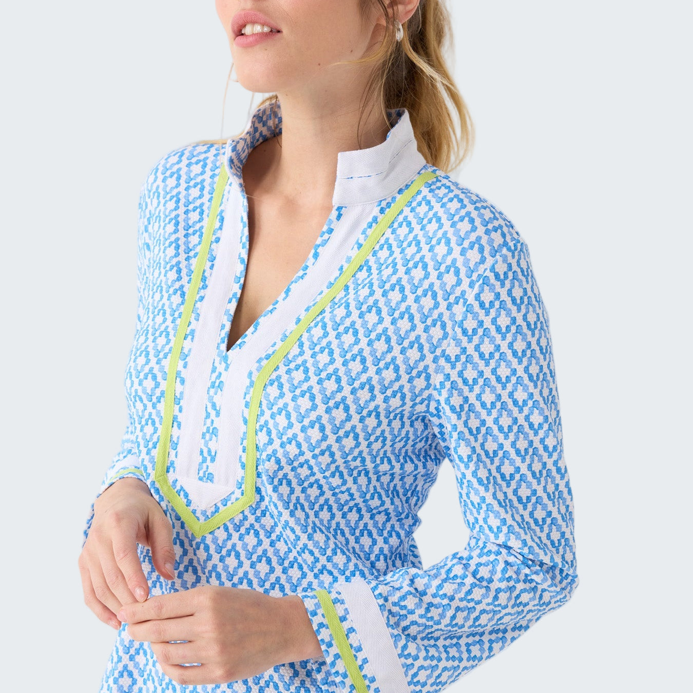 Woman wearing a blue and white patterned dress with green trim on a white background