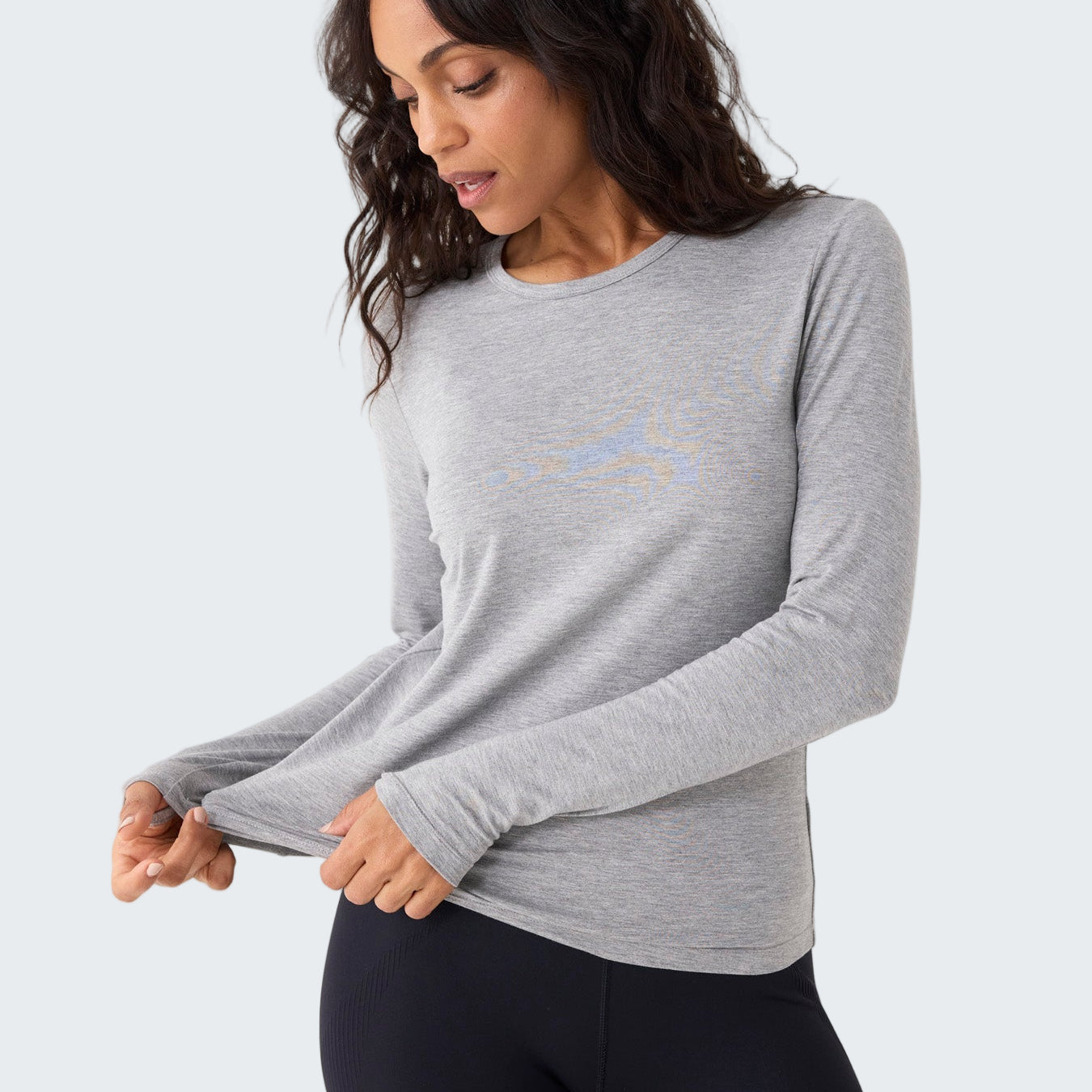 Woman wearing a gray long-sleeve shirt and black leggings on a white background