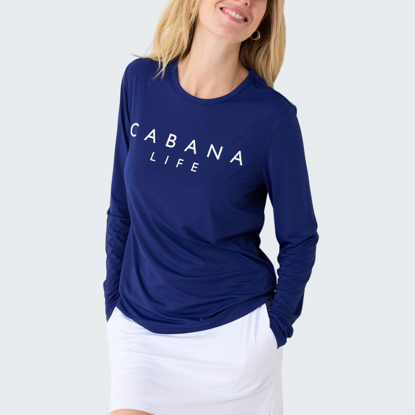 Woman wearing a blue 'Cabana Life' shirt and white skirt on a white background